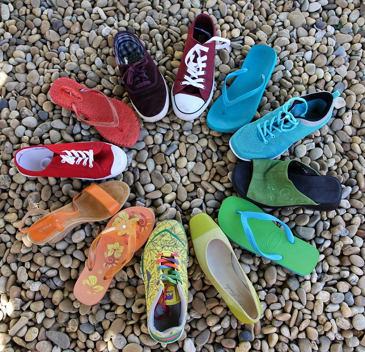 Distintos tipos de calzado de colores formando un círculo sobre una superficie de piedras
